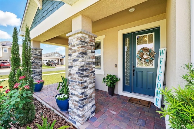 view of exterior entry with a porch and stucco siding