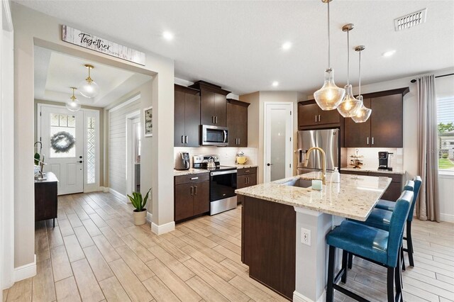 kitchen featuring appliances with stainless steel finishes, a sink, baseboards, light wood-style floors, and recessed lighting