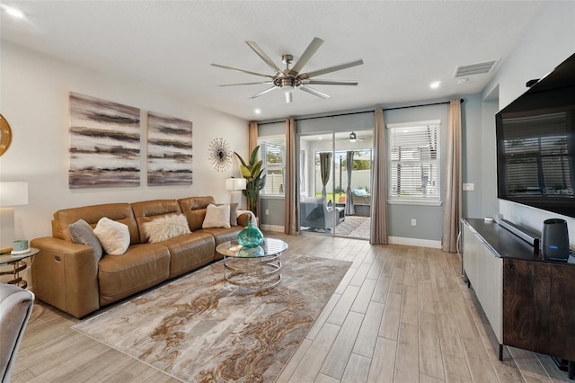 living room with ceiling fan, healthy amount of natural light, light wood-style flooring, and baseboards