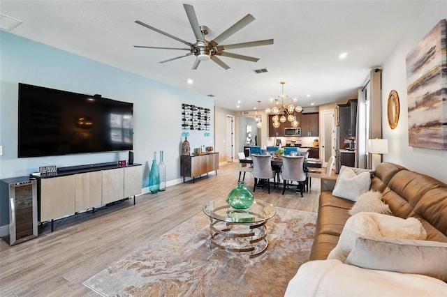 living room featuring light wood-type flooring, a ceiling fan, a chandelier, recessed lighting, and beverage cooler
