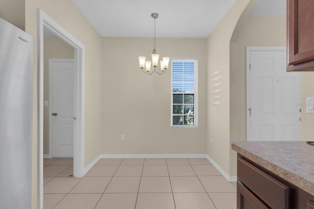 561 Lake Cummings Way, Lake Alfred, FL 33850 - unfurnished dining area featuring a chandelier, light tile patterned floors, arched walkways, and baseboards