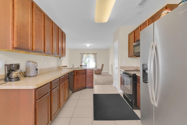 561 Lake Cummings Way, Lake Alfred, FL 33850 - kitchen featuring black appliances, a peninsula, light countertops, light tile patterned floors, and brown cabinets