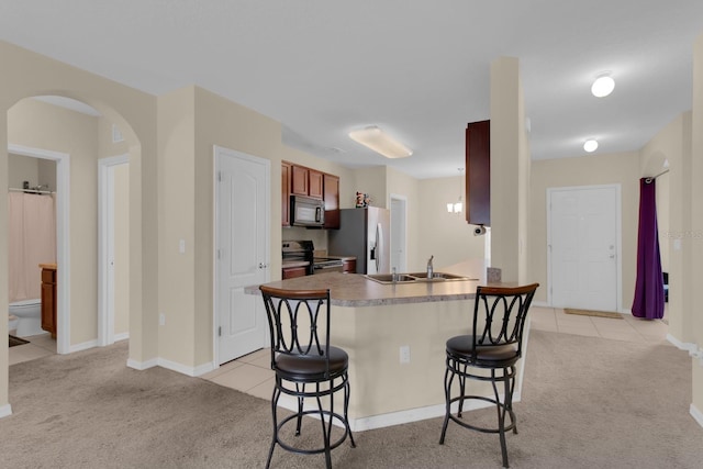 561 Lake Cummings Way, Lake Alfred, FL 33850 - kitchen featuring stainless steel appliances, arched walkways, a breakfast bar, light carpet, and light tile patterned floors