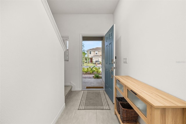 doorway to outside with light tile patterned flooring, baseboards, and stairway
