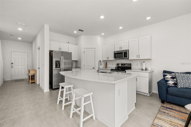 kitchen featuring stainless steel appliances, a sink, white cabinets, light tile patterned floors, and recessed lighting