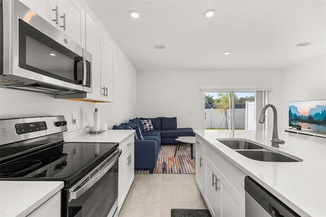 kitchen with stainless steel appliances, a sink, light countertops, white cabinets, and recessed lighting
