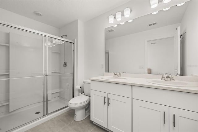 bathroom with a shower stall, tile patterned floors, double vanity, and toilet