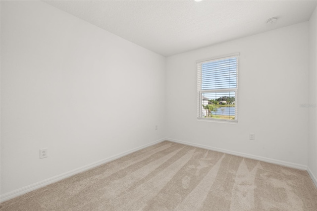 spare room with baseboards, light colored carpet, and a smoke detector