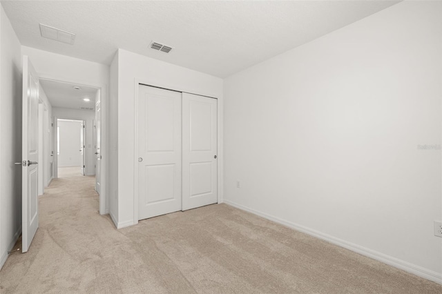 unfurnished bedroom featuring light carpet, baseboards, and a closet