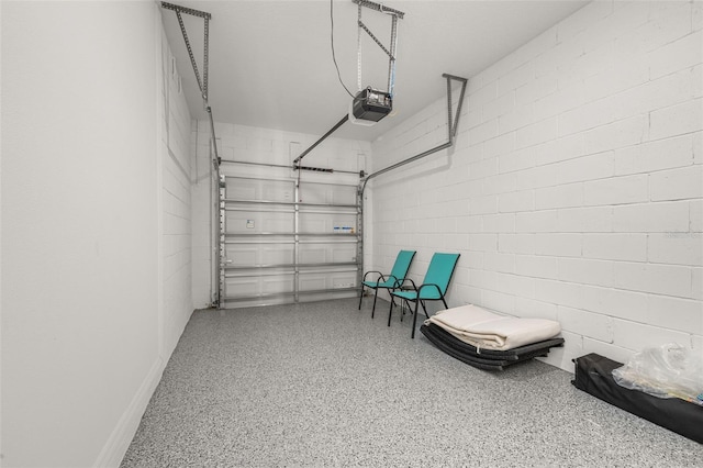 garage with a garage door opener and concrete block wall