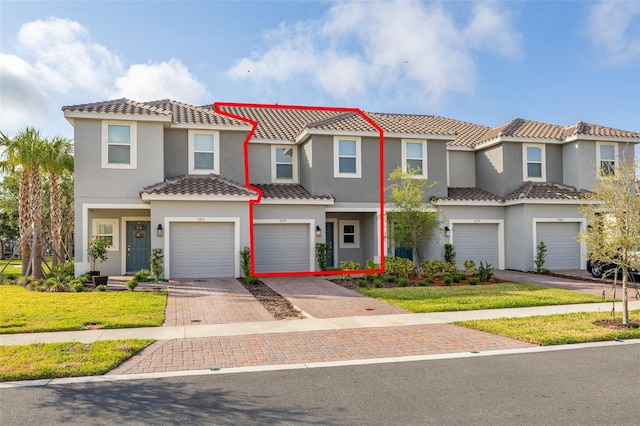 view of property with a garage, a tile roof, driveway, and stucco siding
