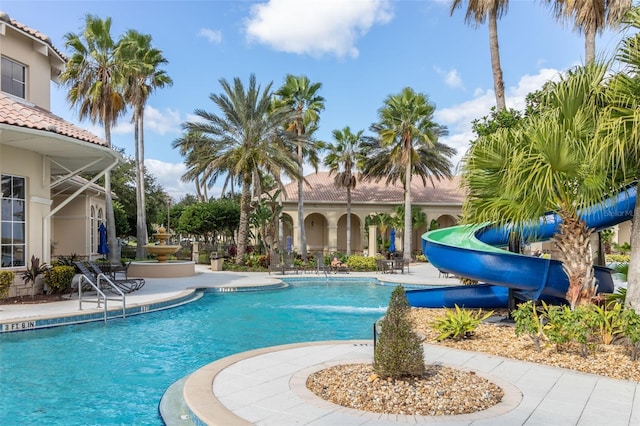 community pool with a water slide and a patio area