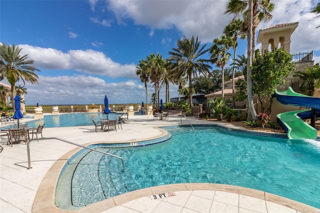 community pool with a water slide and a patio