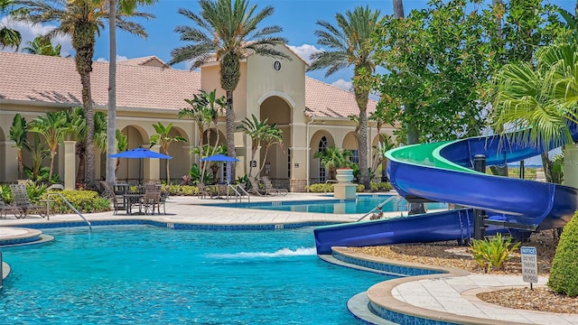 community pool with a water slide and a patio