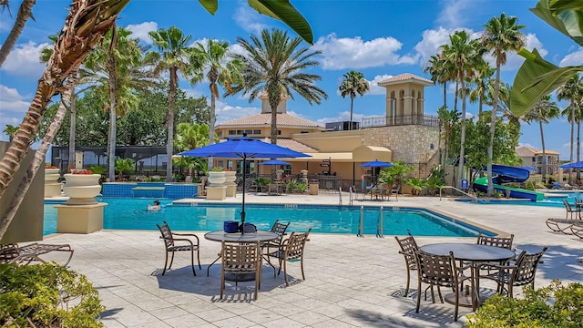 community pool featuring a water slide and a patio