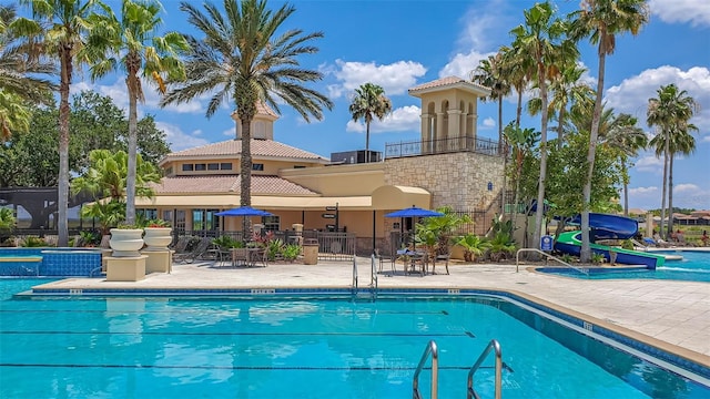 community pool featuring a water slide and a patio area
