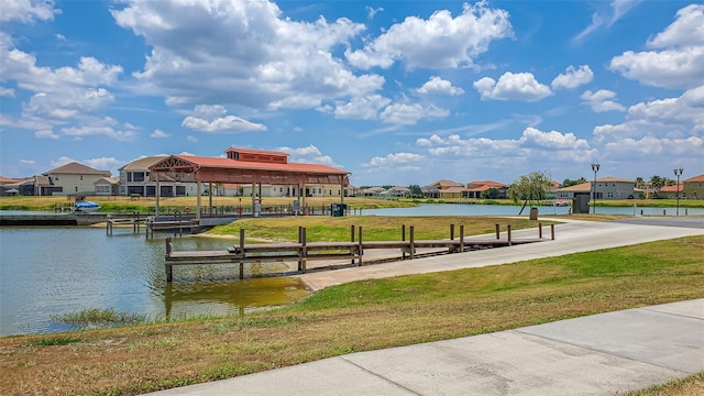 dock featuring a residential view, a yard, and a water view