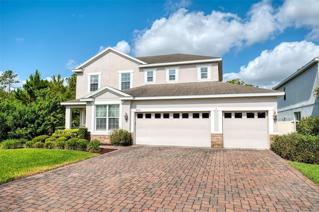 view of front of property with stone siding, an attached garage, decorative driveway, stucco siding, and a front lawn