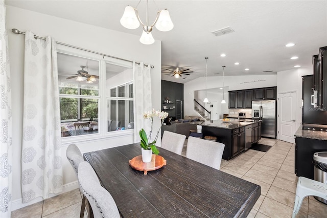 dining room featuring ceiling fan, stairs, light tile patterned floors, and vaulted ceiling