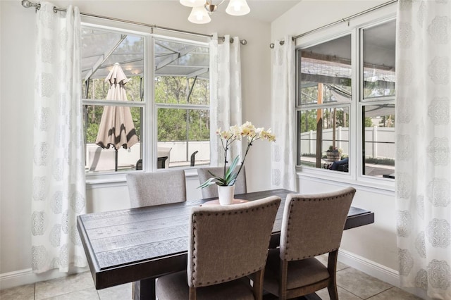tiled dining room with baseboards and a chandelier