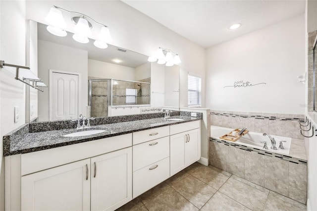 bathroom with a shower stall, a garden tub, double vanity, and tile patterned floors