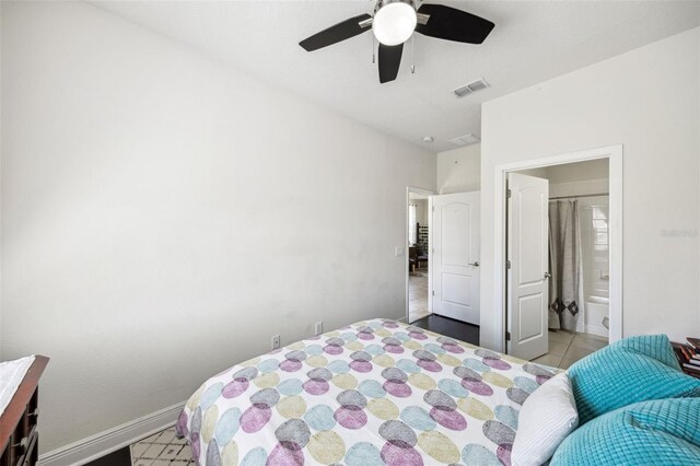 tiled bedroom with baseboards, ensuite bath, and a ceiling fan
