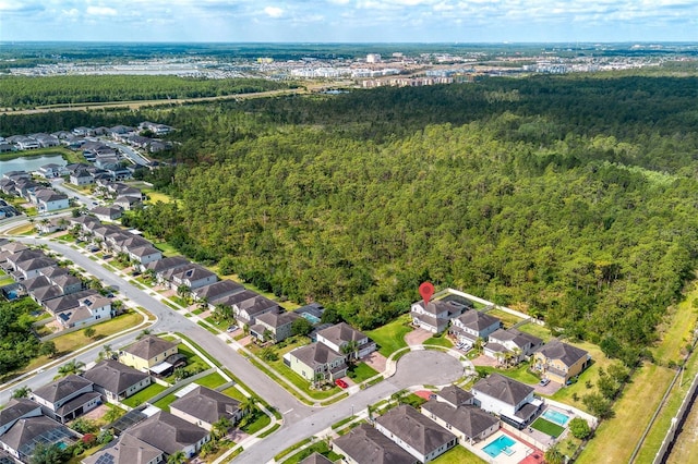 aerial view of property's location featuring a forest and nearby suburban area