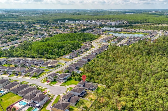 aerial view of property's location featuring a forest, a large body of water, and nearby suburban area
