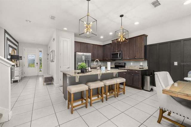420 Burma St, Kissimmee, FL 34747 - kitchen with stainless steel appliances, light tile patterned floors, dark brown cabinets, a kitchen bar, and recessed lighting