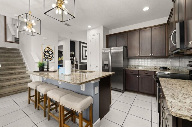 420 Burma St, Kissimmee, FL 34747 - kitchen with appliances with stainless steel finishes, a chandelier, dark brown cabinets, decorative backsplash, and light stone countertops