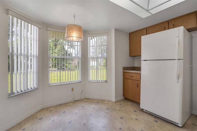 14091 SW 32nd Terrace Rd, Ocala, FL 34473 - kitchen with freestanding refrigerator, plenty of natural light, brown cabinetry, and light countertops