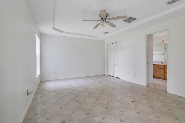 14091 SW 32nd Terrace Rd, Ocala, FL 34473 - unfurnished bedroom featuring a tray ceiling, a textured ceiling, a closet, ceiling fan, and ensuite bathroom