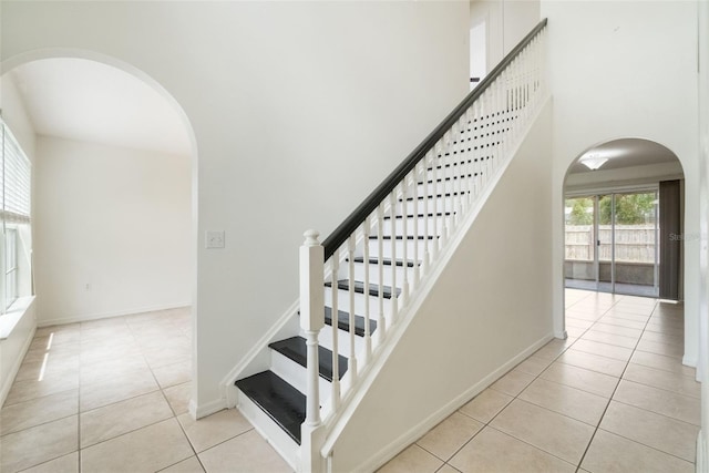 4630 Elena Way, Melbourne, FL 32934 - staircase featuring arched walkways, tile patterned flooring, a towering ceiling, and baseboards