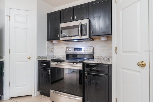 4630 Elena Way, Melbourne, FL 32934 - kitchen featuring stainless steel appliances, dark cabinetry, decorative backsplash, and light tile patterned floors