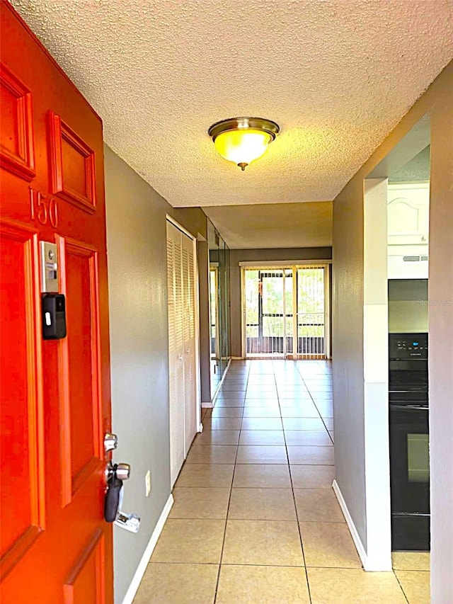 2864 N Powers Dr Unit 150, Orlando, FL 32818 - hallway featuring light tile patterned floors, baseboards, and a textured ceiling