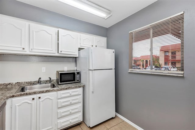 2864 N Powers Dr Unit 150, Orlando, FL 32818 - kitchen featuring stainless steel microwave, freestanding refrigerator, a sink, white cabinetry, and light tile patterned floors