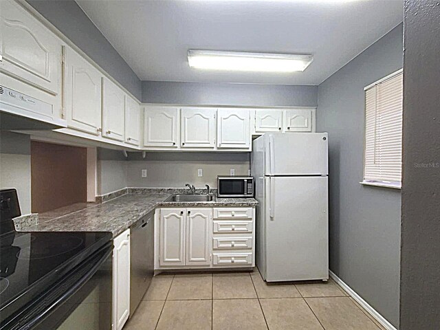 2864 N Powers Dr Unit 150, Orlando, FL 32818 - kitchen featuring appliances with stainless steel finishes, a sink, white cabinetry, light tile patterned flooring, and baseboards
