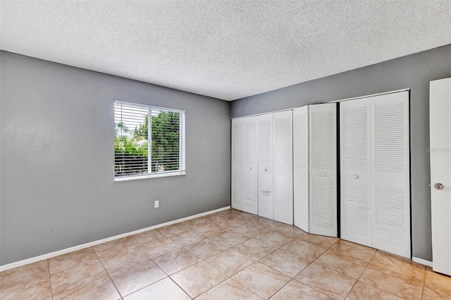 2864 N Powers Dr Unit 150, Orlando, FL 32818 - unfurnished bedroom with a textured ceiling, two closets, light tile patterned flooring, and baseboards