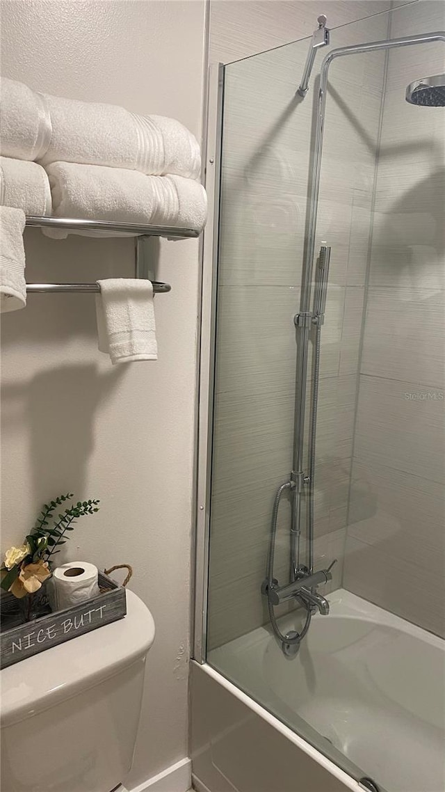 5245 W Irlo Bronson Memorial Hwy Unit 148, Kissimmee, FL 34746 - bathroom featuring shower / bath combination with glass door, toilet, and baseboards