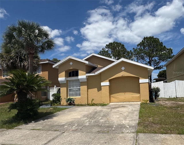 view of front facade featuring stucco siding, a garage, driveway, and fence