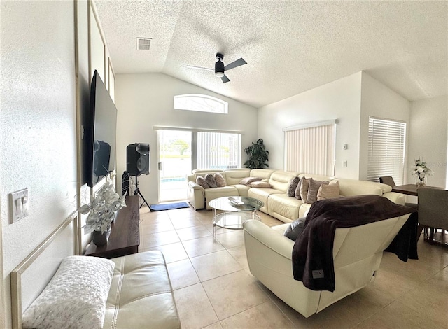 living area with vaulted ceiling, a ceiling fan, a textured ceiling, and light tile patterned floors