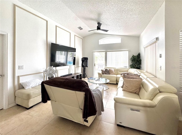 living room with ceiling fan, vaulted ceiling, light tile patterned flooring, and a textured ceiling