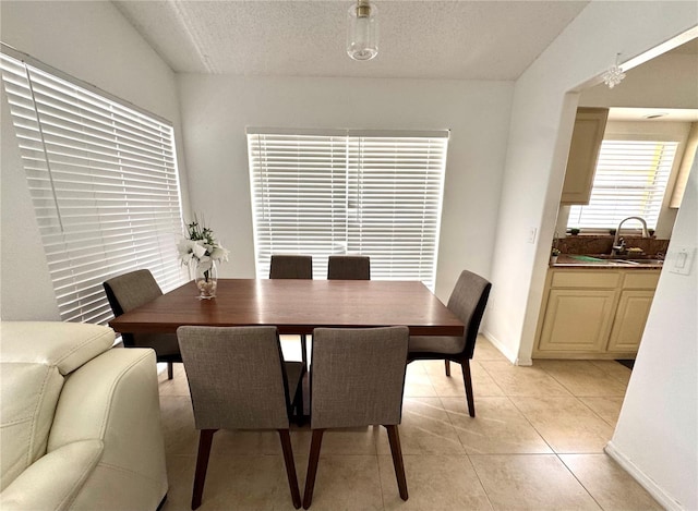 dining area with a textured ceiling, light tile patterned flooring, and baseboards