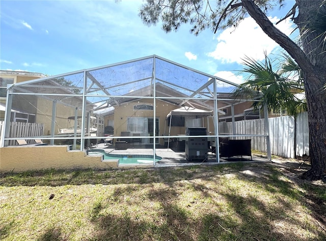 rear view of house featuring a patio area, fence, and glass enclosure