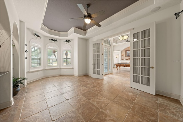 1654 Marina Lake Dr, Kissimmee, FL 34744 - empty room featuring ornamental molding, a tray ceiling, a ceiling fan, french doors, and stone finish floors