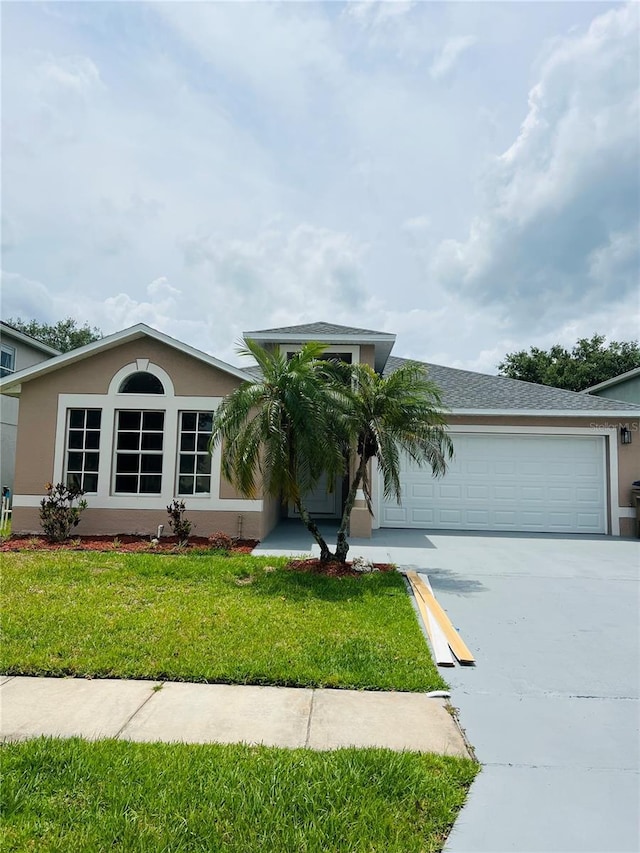 ranch-style home featuring driveway, an attached garage, a front yard, and stucco siding