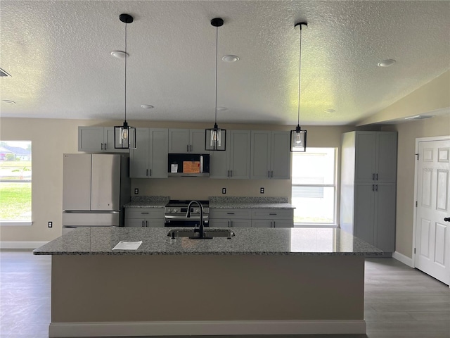 kitchen with freestanding refrigerator, a sink, black microwave, baseboards, and a textured ceiling