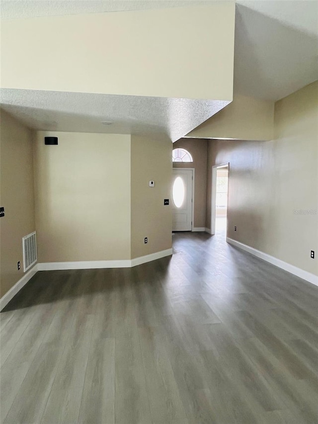 unfurnished living room featuring dark wood-type flooring and baseboards