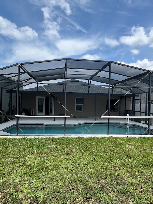 swimming pool with a yard and glass enclosure