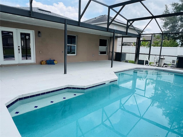 outdoor pool featuring a patio, french doors, fence, and glass enclosure